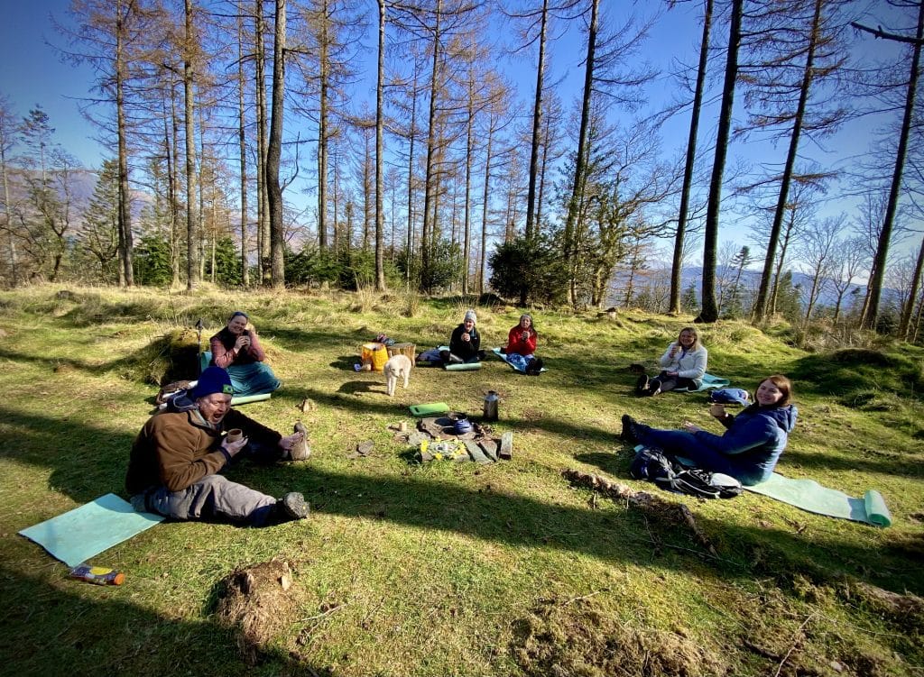 People drinking tea during a forest bathing session in Whinlatter Forest, Cumbria.